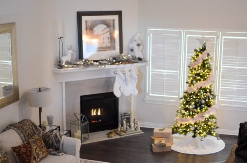A cozy living room with a fireplace and a decorated Christmas tree.