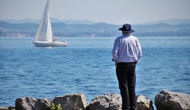 a retired man looking at the sea and a boat.