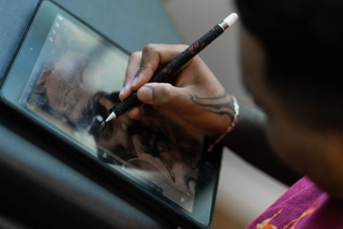 An artist holding a tablet and a pen, making a work in progress