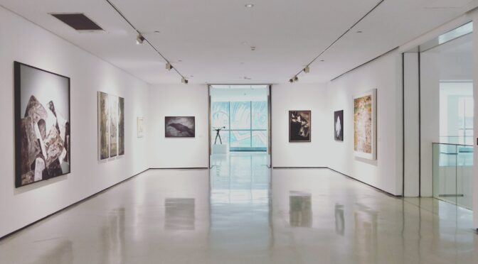 A gallery with white walls and big paintings.