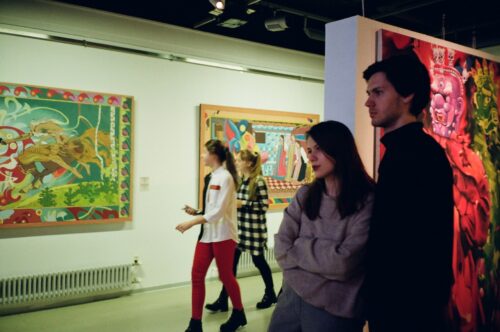 A man and a woman looking at a painting in a gallery.