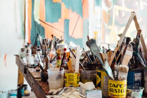 A table full of cups with paintbrushes.