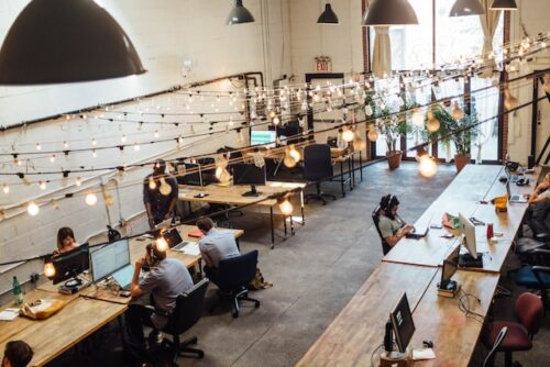  people in coworking space with ceiling lightbulbs depicts remote work in Miami