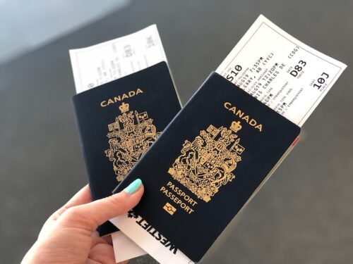 A person holding two Canadian passports with plane tickets.