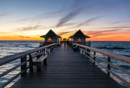 People walking along a dock during the sunset