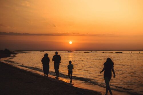 A family walking down the beach and having fun during a sunset